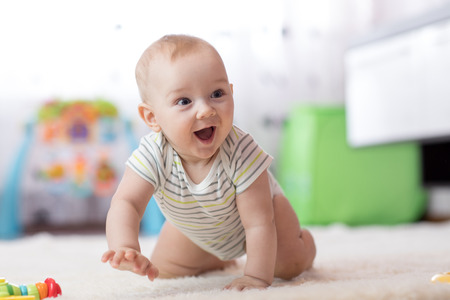 crawling funny baby boy in nursery at homeの写真素材