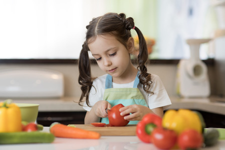 Adorable little girl helping at kitchen with salad makingの写真素材