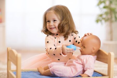 Cute kid girl playing doctor with doll at homeの写真素材
