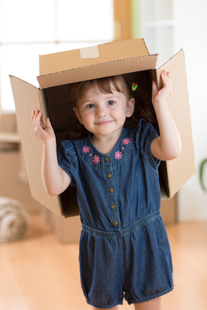 Happy child playing with boxes after moving in new houseの写真素材