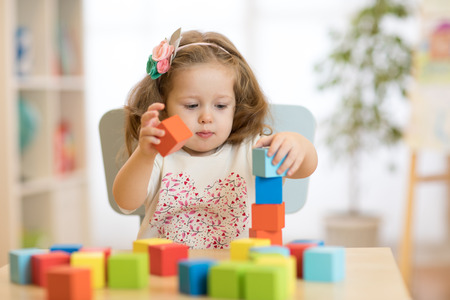 child girl playing with block toys in day care centerの写真素材