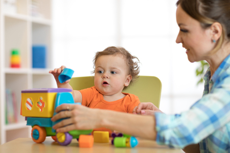 kid and woman playing with puzzle toy in daycare or kindergartenの写真素材