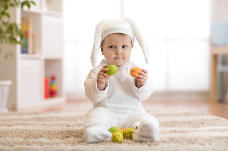 Cute little baby in bunny costume playing at homeの写真素材