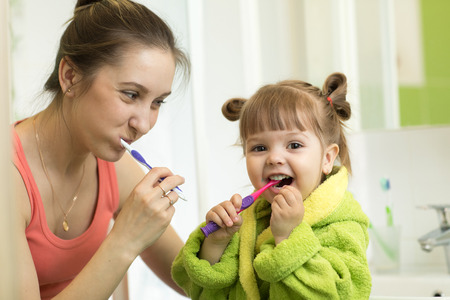 mother and little daughter brushing teeth in bathroomの写真素材