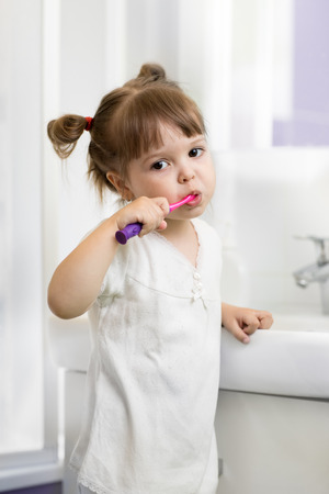 Child toddler girl brushing teeth in bathroomの写真素材