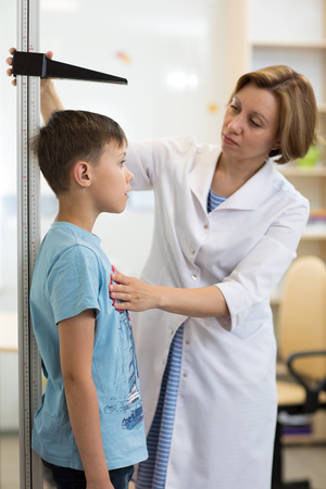 Doctor measures growth kid boy in medical office, profileの写真素材