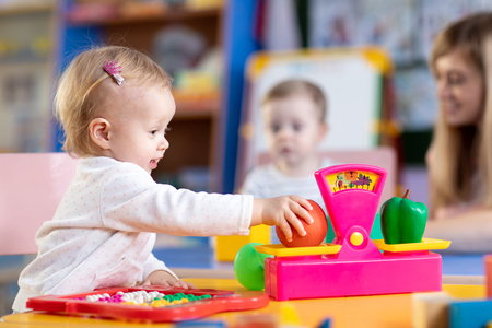 Kids with preschool teacher play role game in toy shop at home or kindergartenの写真素材