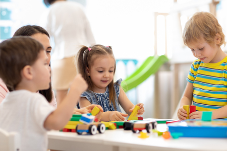 Kids playing with educational toys in kindergarten. Nursery teacher looking after childrenの写真素材