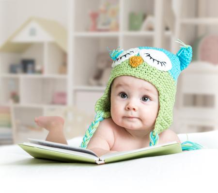 baby in funny owl knitted hat owl with book in nursery