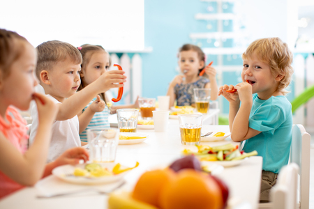 Group of kindergarten kids eating healthy food lunch break togetherの写真素材
