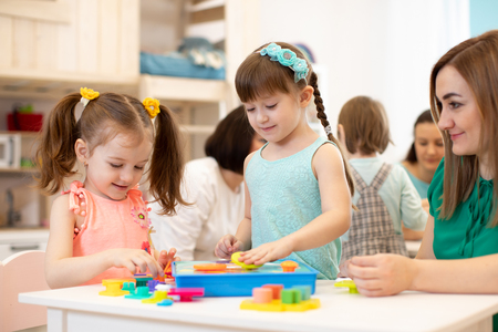 Kids with teacher playing with developmental toys in kindergartenの写真素材