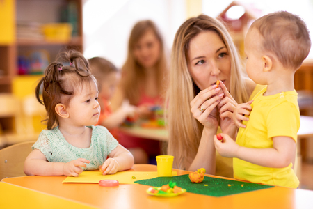 Little kids molded from clay toys. Teacher plays with children.の写真素材