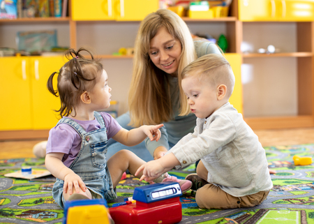 Babysitter plays with babies in nurseryの写真素材