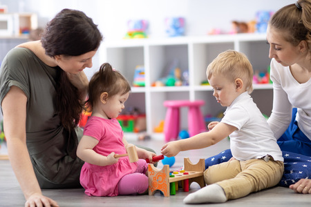 Group of babies playing together with mothers in the classroom in nursery or preschoolの写真素材
