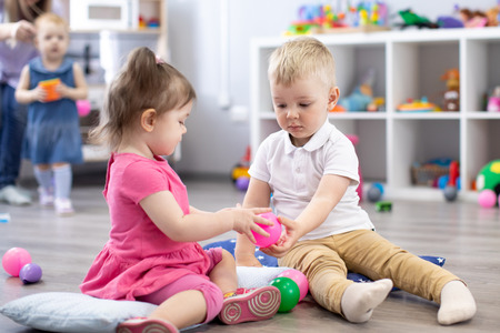 Little toddlers boy and a girl playing together in nursery room. Preschool children in day care centre