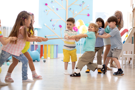 group of kids play and pull rope together in daycareの写真素材