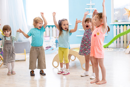 Group of emotional friends with their hands raised. Kids have fun pastime in daycareの写真素材