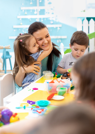 Teacher with kids working with plasticine at kindergarten or playschoolの写真素材