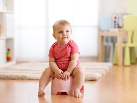 Little smiling girl sitting on a pot. Isolated on white background.の写真素材