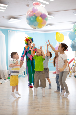 holidays, childhood and celebration concept - several kids having fun and jumping on birthday party in entertainment centreの写真素材