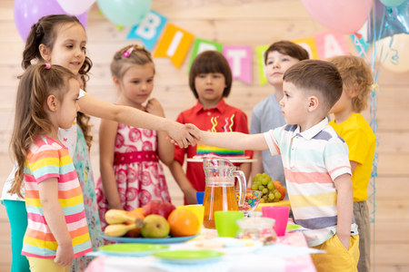 Groups of children come to parties and shake hands with a birthday boy. Kids have come to congratulate their friendの写真素材