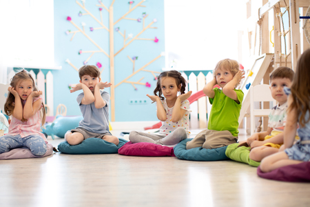 Kids seating on floor and show gestures making taskの写真素材