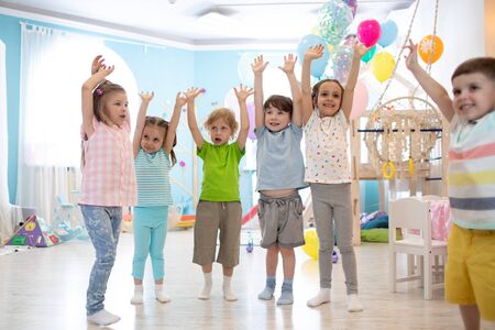 Happy kids with hands up at daycareの写真素材