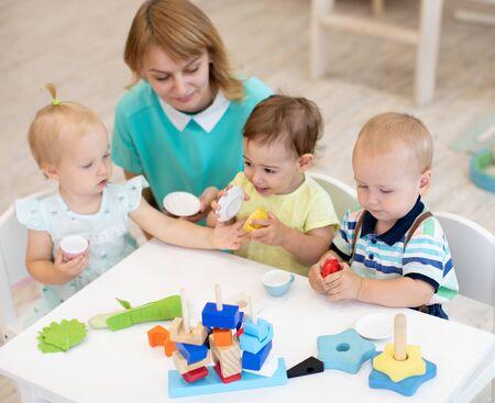 Nursery school children and teacher play with toysの写真素材