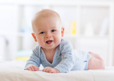 infant baby five months age lying on belly in white sunny nurseryの写真素材