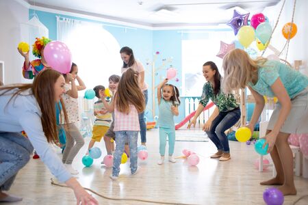Little children and parents playing together on birthday partyの写真素材