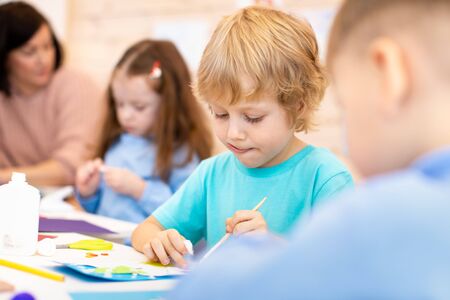 kindergarten children doing arts and crafts with teacher in day care centreの写真素材