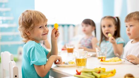 kids eating healthy food in kindergarten or daycareの写真素材