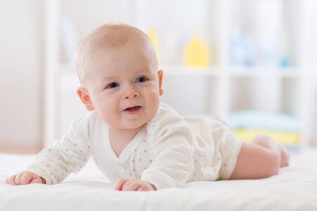 Cute baby boy lying on belly in nursery roomの写真素材