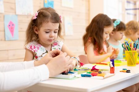 Art and craft activity in kindergarten. Group of preschool kids hands working in daycare center.の写真素材