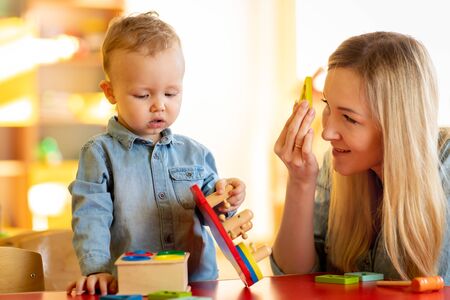 Cute woman and kid playing educational toys at kindergarten or daycareの写真素材