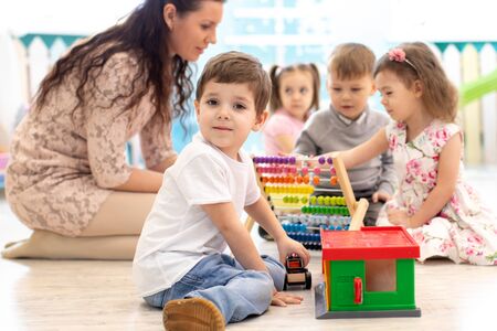 Preschool teacher and children in kindergartenの写真素材