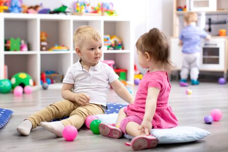 Children playing with colorful toys. Little kid girl and toddler boy with educational toy blocks. Children play at day care or preschool.の写真素材
