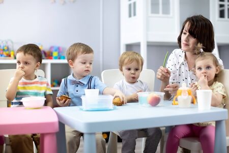 kids group have lunch with teacher in nurseryの写真素材