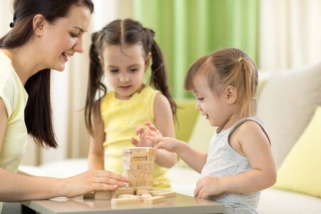 Mother with kids play jenga game in living roomの写真素材