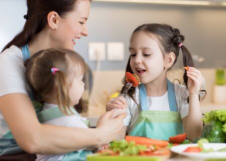 Child tasting food during cooking with their motherの写真素材