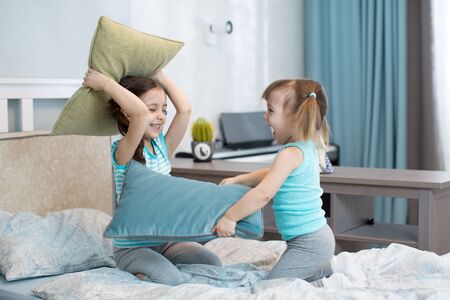 Little girls play using pillows in bedroomの写真素材