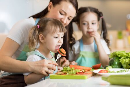 Mom with daughters chopping vegetables in domestic kitchenの写真素材