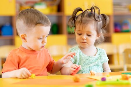 Toddlers boy and girl playing at table with educational toys. Children infants at home or daycare.の写真素材