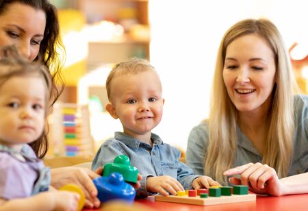 Children with moms play with color wooden puzzle in a montessori classroomの写真素材