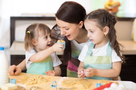 Mother and little daughters weared aprons making cookiesの写真素材