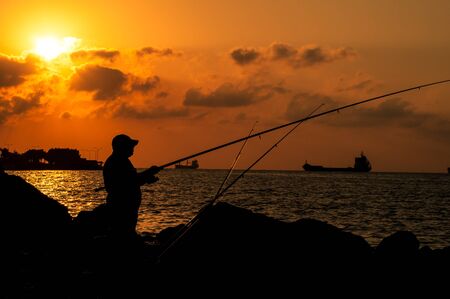 fisherman on the background of the sea at sunset in summerの写真素材
