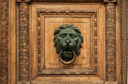 details of an old wooden carved door with a lion-shaped handleの写真素材