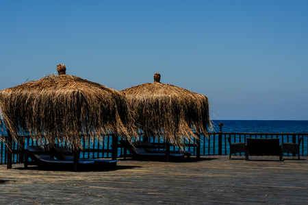 tropical beach with umbrellas of dry palm leaves with sea viewの写真素材