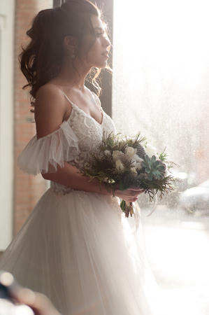 Bride in a white wedding dress with a christmas bouquet of flowers closeupの写真素材
