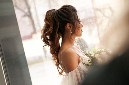 bride with dark hair in a white wedding dress with a bouquet of flowersの写真素材